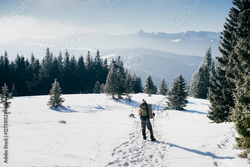 Man in bright clothes with a backpack walking the snow-covered f