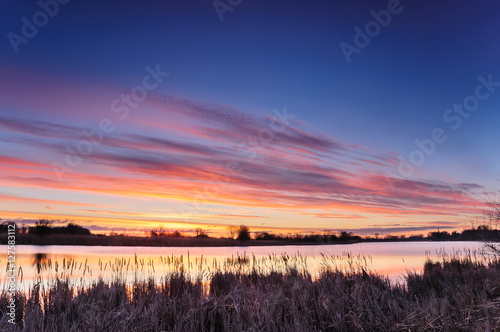 Dawn with colorful clouds over a wild pond in autumn morning