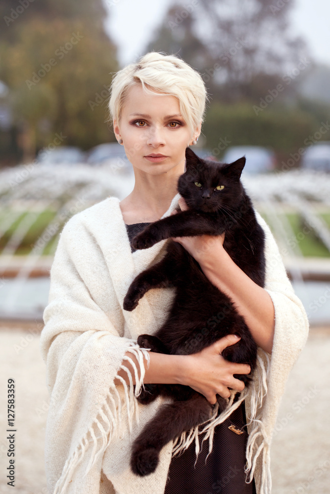 a beautiful blonde woman with a black cat, holding a black cat, stroking a cat