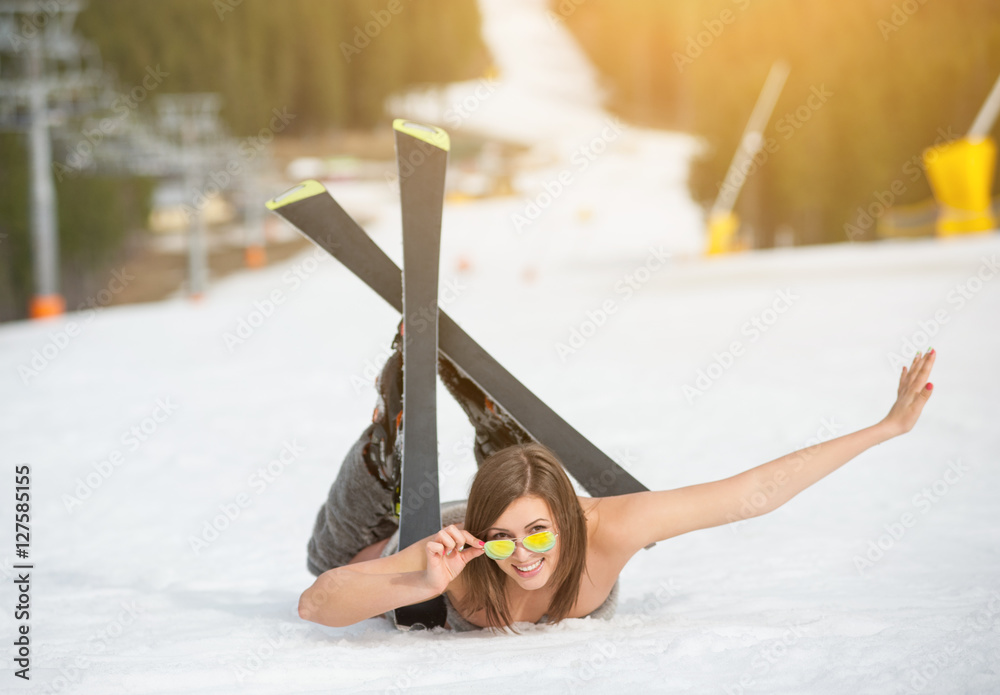 Young happy naked female skier is lying on snowy slope near ski lift at ski  resort. Beautiful woman is wearing skis, boots and sunglasses. Spring is  coming Stock Photo | Adobe Stock