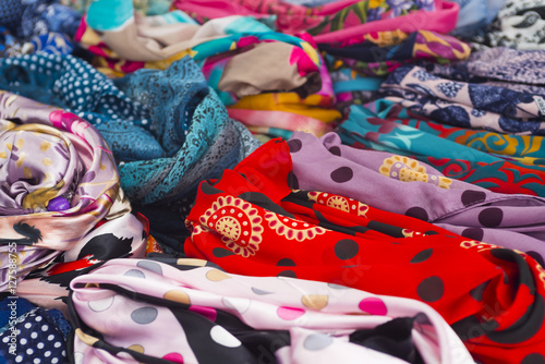 Rows of colorful silk scarves lie on a market stall © ulkan