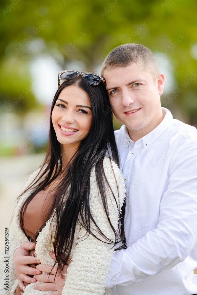 Naklejka premium Portrait of beautiful young couple in love, background outdoor