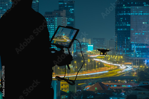 Silhouette of Man using drone to monitor the city  night traffic.