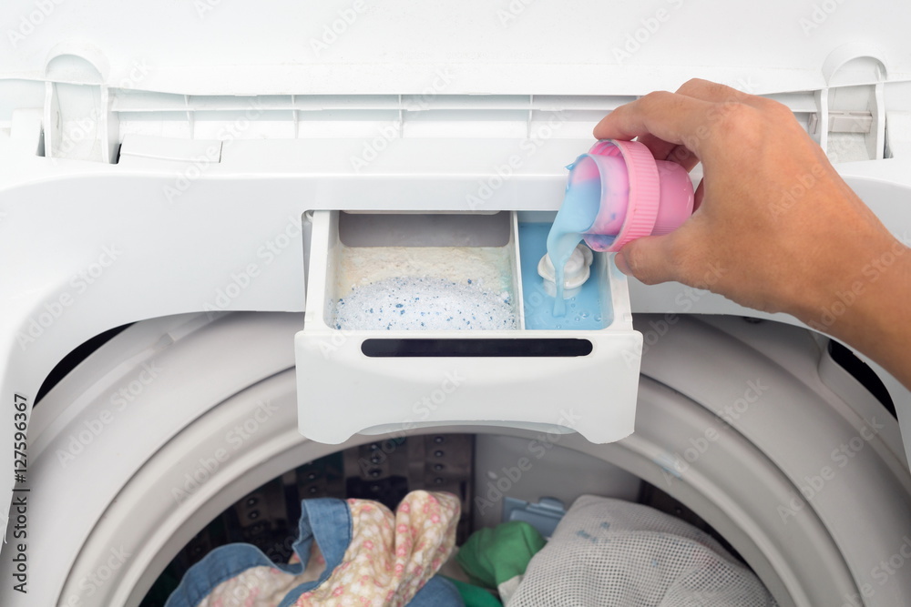 Hand holding fabric softener in washing machine. Stock Photo | Adobe Stock