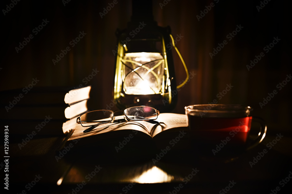 The light of kerosene lamp and open book on the table