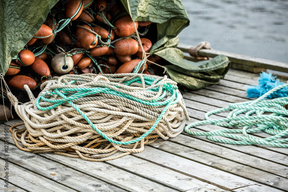 Many fishing nets and floats, stacked on a wooden dock. Fisheries, fishing. Fishing industry.  Background.
