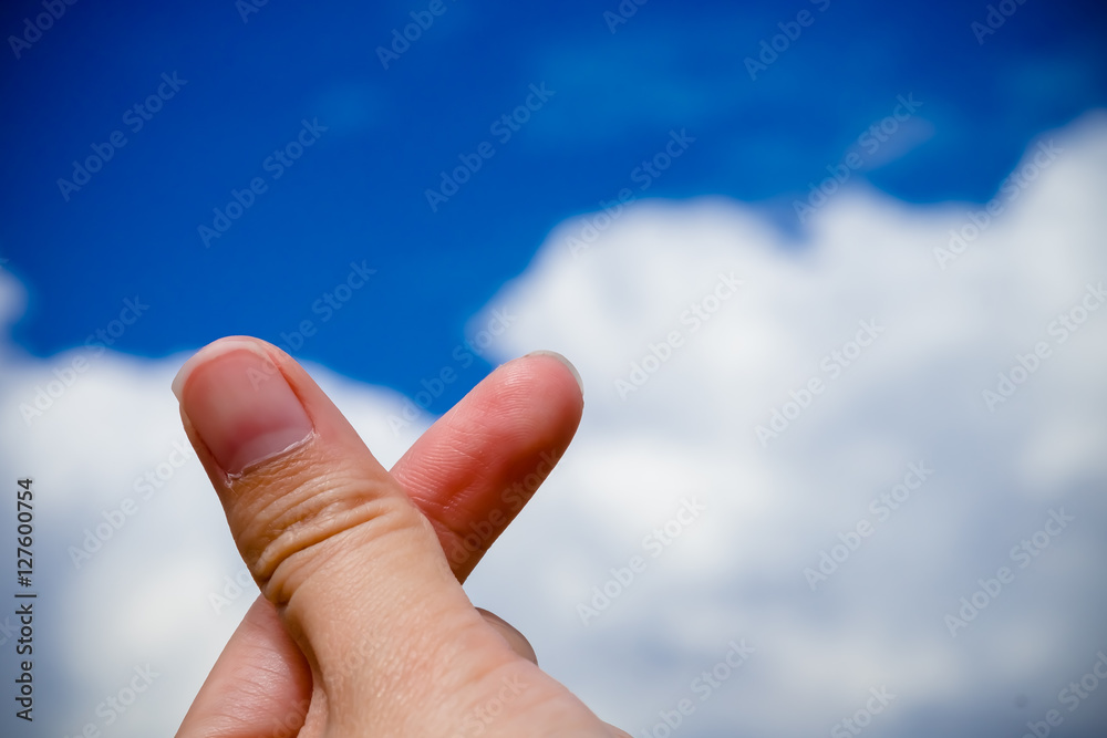Finger heart sign, mini heart against blue sky