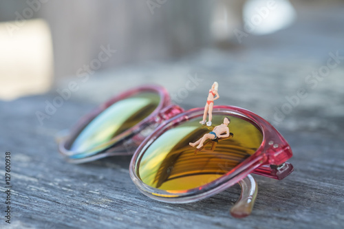 Miniature people in swimsuit relax on the sunglasses near swimmi photo