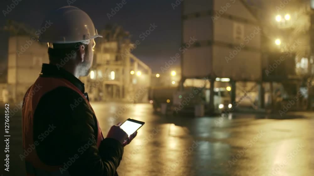 Engineer in hardhat checking the loading of truck with a tablet computer on heavy industry factory