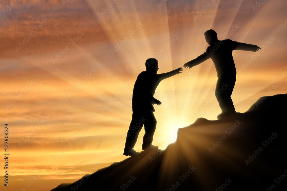Climber helps friend in mountains of giving helping hand sunset Climber helps friend in mountains of giving helping hand sunset
