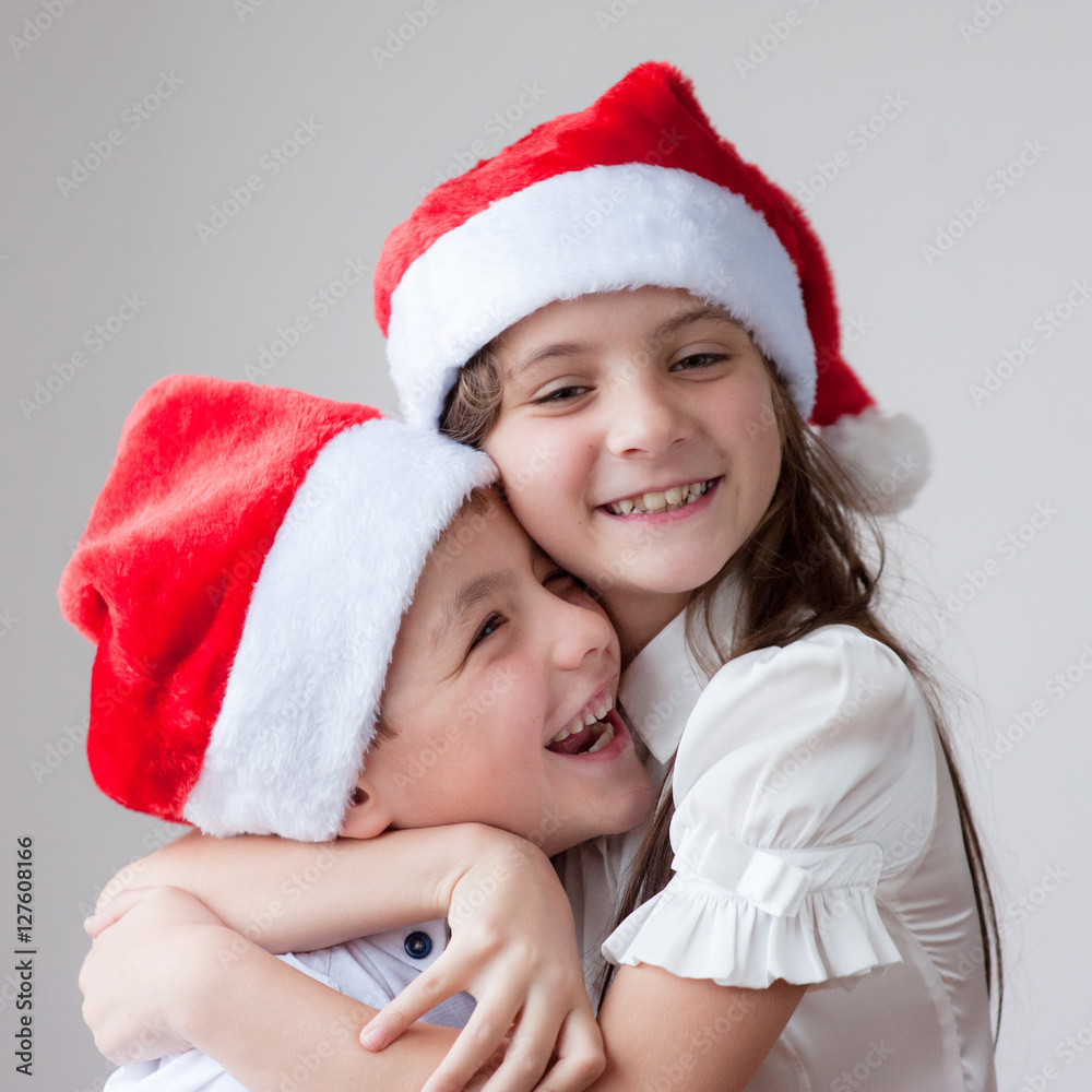 smiling kids in Santa hats hugging smiling kids in Santa hats hugging