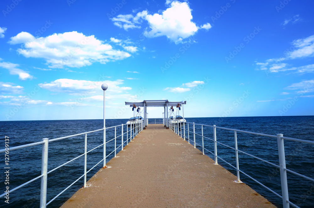 Jetty stretching into the sea with a beautiful blue sky and clouds in summer in Bulgaria Golden Sands resort. Pierce empty road in the beautiful sea and sky.