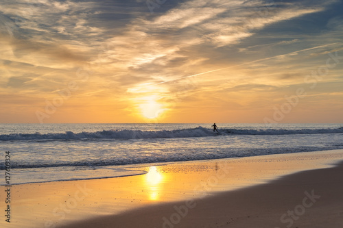 Surfer in the sea, on a background of the sunset rides. © sergojpg