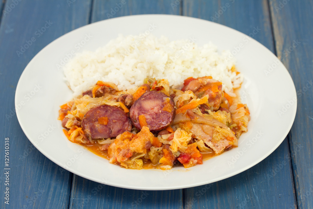 meat with sausages, cabbage and rice on white plate on wooden background meat with sausages, cabbage and rice on white plate on wooden background