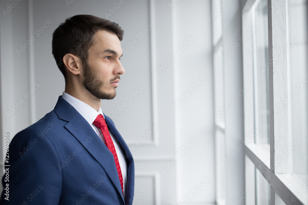 Businessman in white office thinking standing at window Businessman in white office thinking standing at window