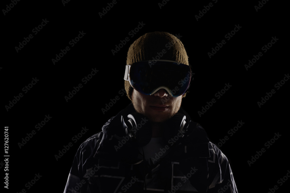 Snowboarder in mask on black background. Dark concept with backlight. Extreme sport live.