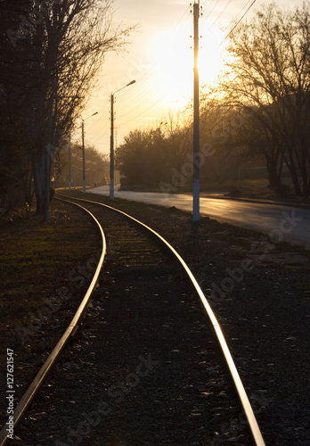 Железнодорожный путь идущий вдоль дороги на закате