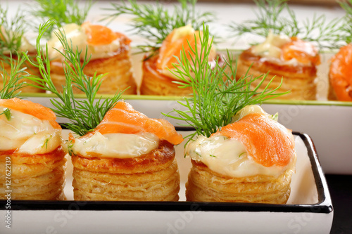 Salmon appetizer with dill dip in puff pastry on stone tray