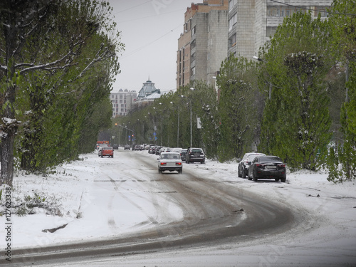 A first snow on the city road with cars