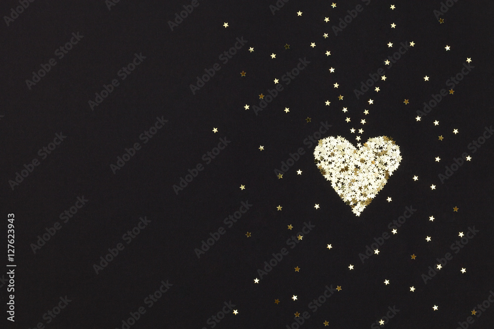 Small golden heart  made of little stars on black background. Christmas concept