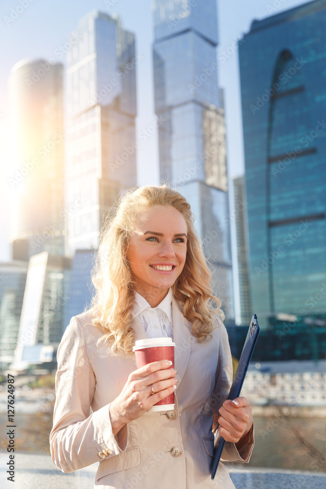 Fototapeta premium Young attractive business woman holding folder and cup of coffee