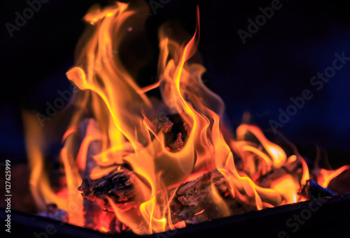 Dance of flames against a dark background, wood burning grill in the open fire.