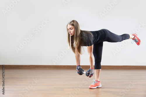 Young woman makes exercises with weight in gym