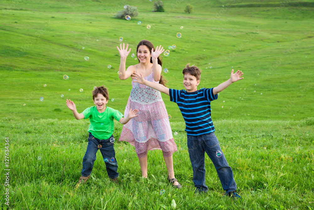 Three happy kids catch the soap bubbles on lawn Three happy kids catch the soap bubbles on lawn