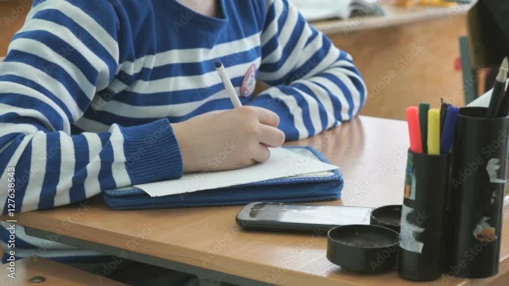 The pupil writes the text on the sheet of paper The pupil writes the text on the sheet of paper