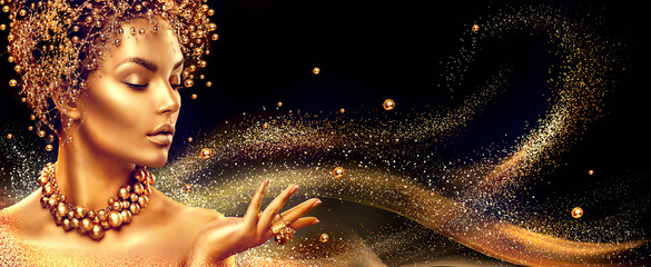 Golden woman. Beauty fashion model girl with golden make up, hair and jewellery on black background