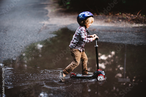 boy on scooter in puddle