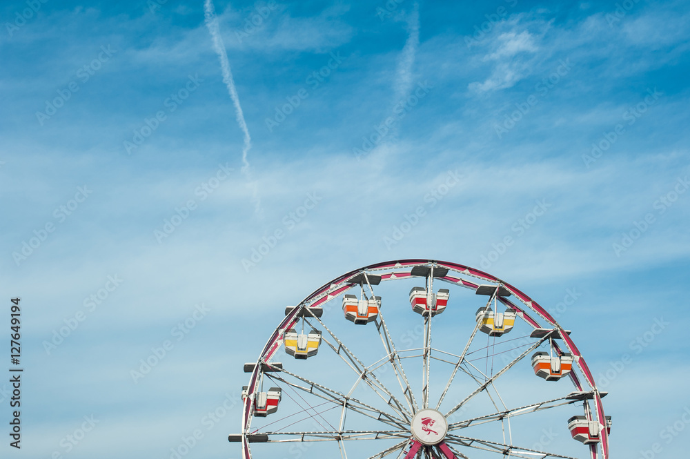 Vintage colorful ferris wheel against a sunny blue sky. Retro fun at a summer fair or a carnival.