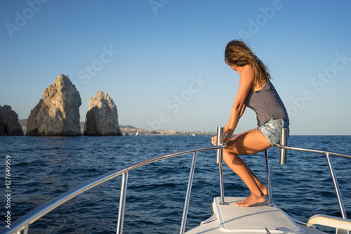 Young woman in the boat at sunset near the rock formations around the Arch in Cabo San Lucas, Mexico.