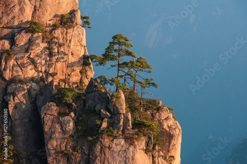 Sunrise from Lion Peak, Huangshan Mountain, China. Early morning sun lights the cliffs below and observation deck at Lion Peak, Yellow Mountains. Mountain range dissolves in the layers of atmosphere.