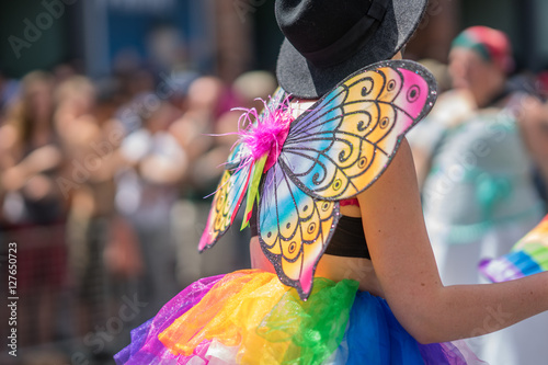 Young woman in a crowd celebrating Pride Parade. Wearing colorful rainbow butterfly wings and a bright tutu skirt. Supporting marriage equality and LGBT rights.