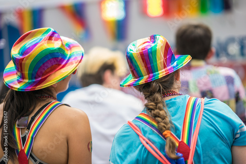Young brunette woman in a crowd celebrating Pride Parade. Wearing colorful rainbow accessories. Soap bubbles floating around her. Supporting marriage equality and LGBT rights.