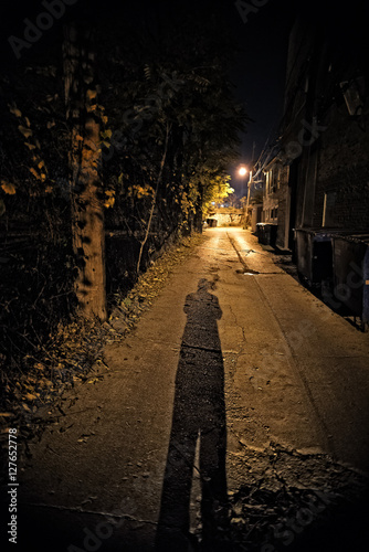 Shadow of a Person in a Dark City Alley at Night