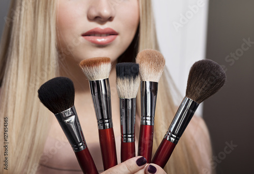 Fotografie beautiful young blond woman and brush for makeup
