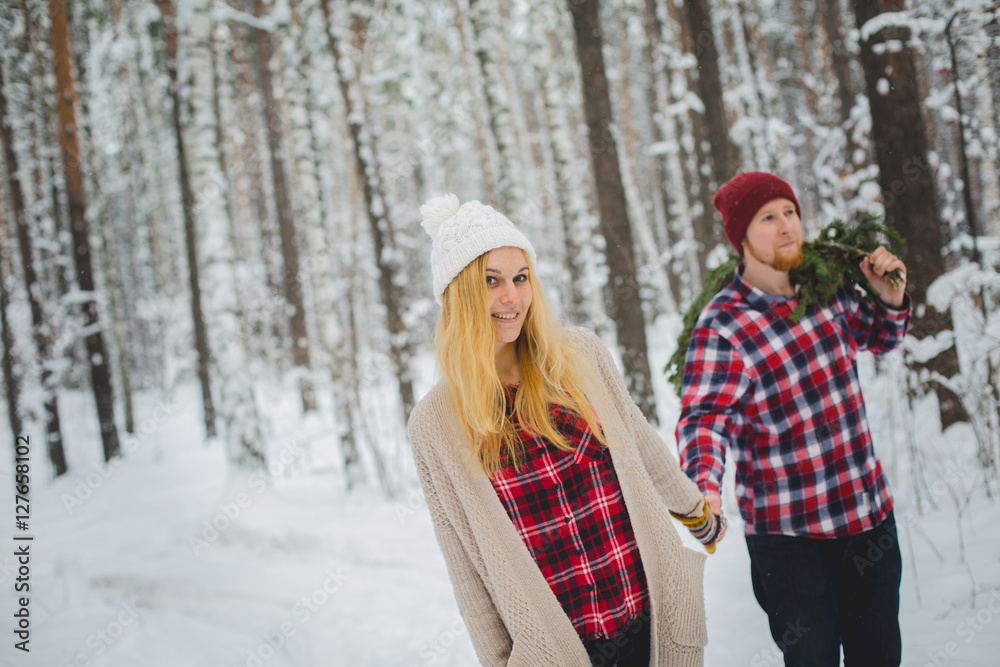 young couple with fir twigs walk in the winter woods