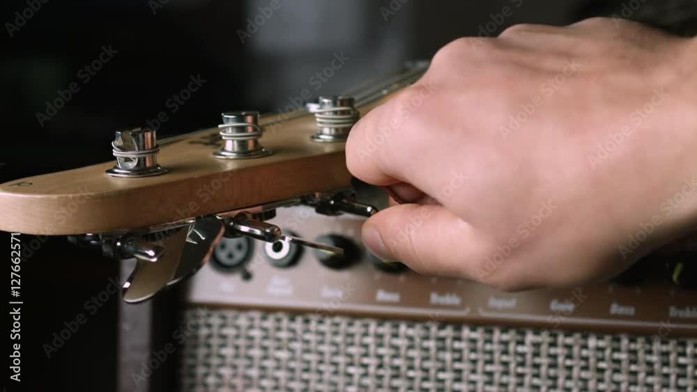 Close up of hand turn bass guitar tuning peg Close up of hand turn bass guitar tuning peg