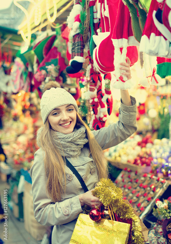 Happy glad girl choosing Christmas decoration at market