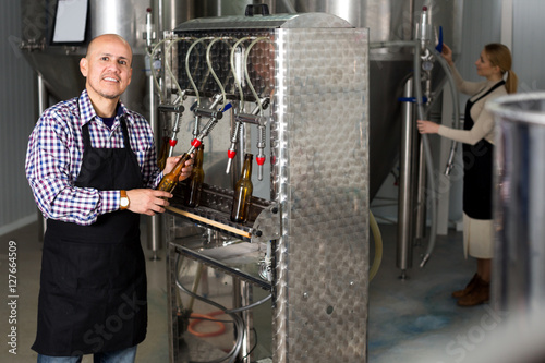 Man employee bottling beer in glass bottles