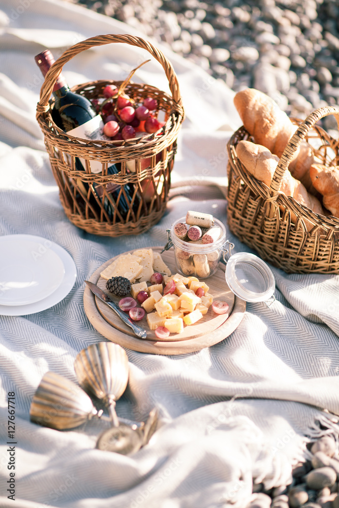 Picnic background with basket, wine and fruits by the ocean Picnic background with basket, wine and fruits by the ocean