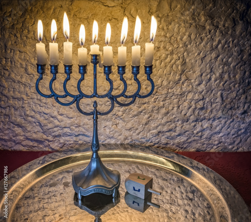 Menorah with the glitter lights of candles and wooden dreidel are traditional Jewish attributes and symbols for Hanukkah holiday. Selective focus. Image toned and filtered for retro style photo