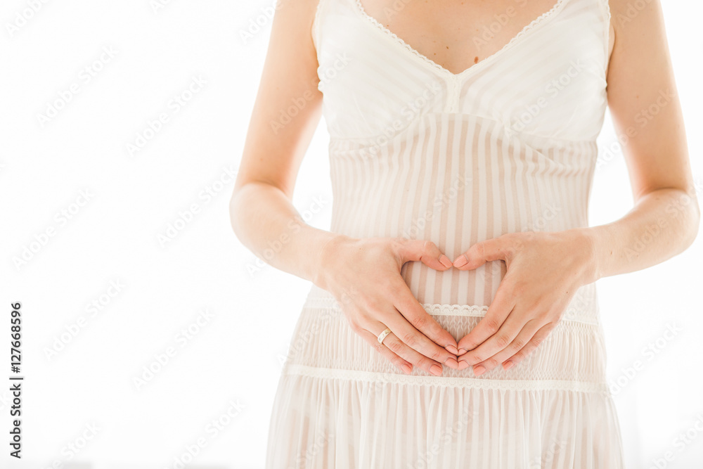 Pregnant Belly with fingers Heart symbol. Beautiful Young Pregnant in white dress Pregnant Belly with fingers Heart symbol. Beautiful Young Pregnant in white dress