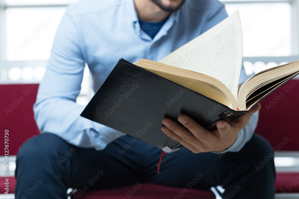 young male college student reading in the library young male college student reading in the library