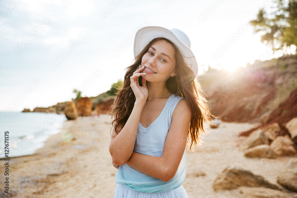 Smiling beautiful young woman standing on the beach Smiling beautiful young woman standing on the beach