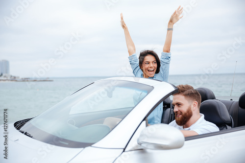 Happy young couple enjoying road trip in their convertible