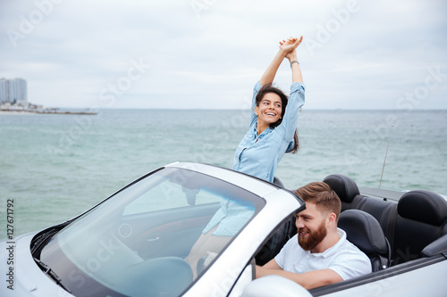 Young couple on road trip driving in convertible car