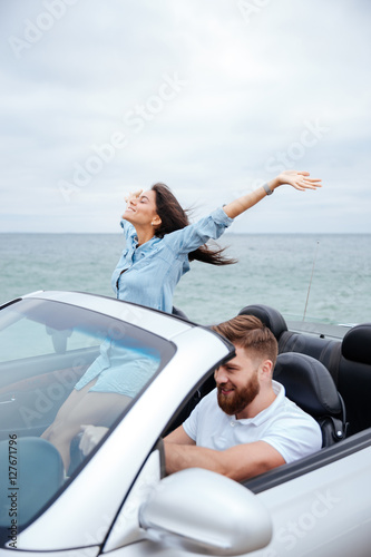 Young couple on road trip driving in convertible car
